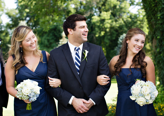 Groom with smiling bridesmaids in navy dresses outdoors