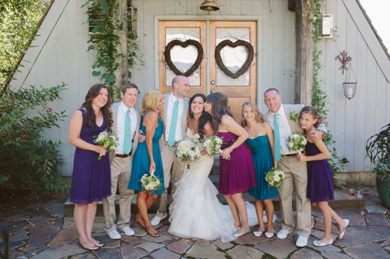 Wedding party posing joyfully outside rustic venue