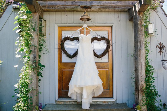 Wedding dress hangs on door with heart wreaths decor