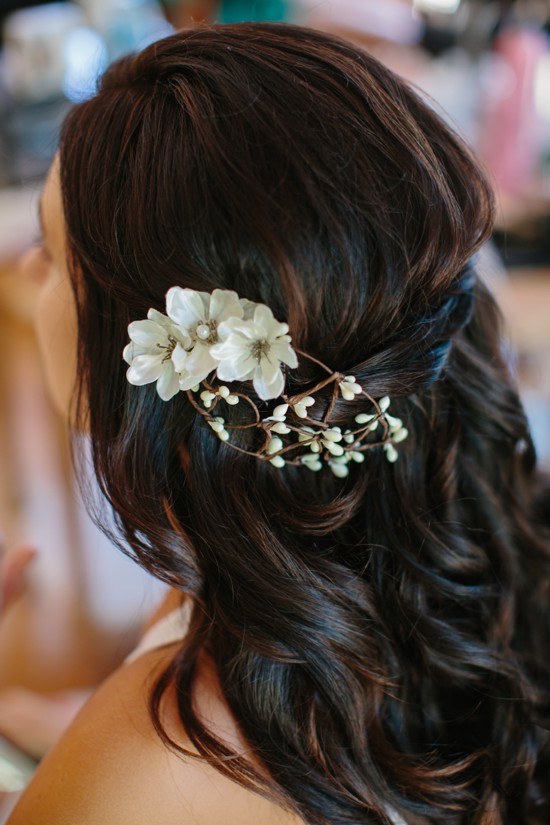 Woman with long brown hair adorned with white flower hairpiece