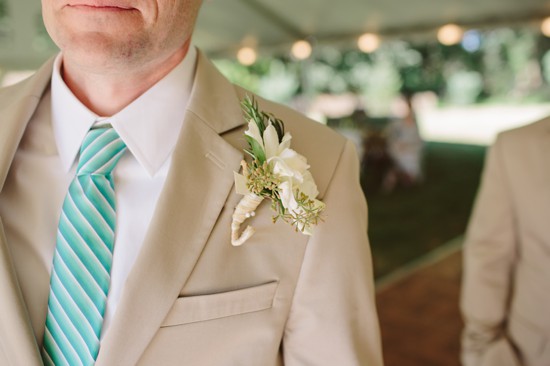 Groom in beige suit with floral boutonniere and teal tie
