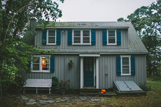 Gray home with blue shutters pumpkin on porch