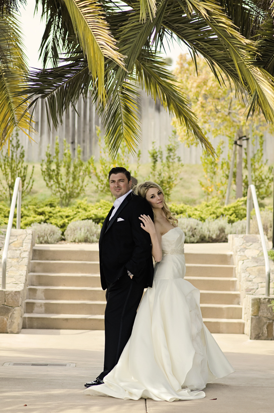 Bride and groom embrace near palm tree on wedding day