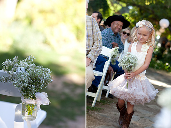 Flower girl in cowboy boots walking down the aisle at a wedding