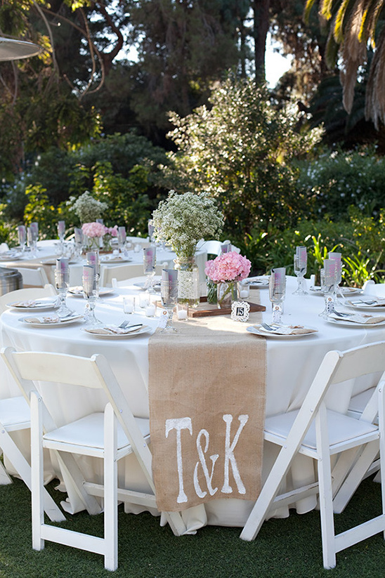 Outdoor wedding reception table with floral centerpieces and initials