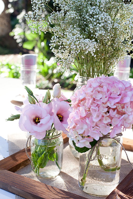Pink flowers in mason jars arranged on a table for a wedding