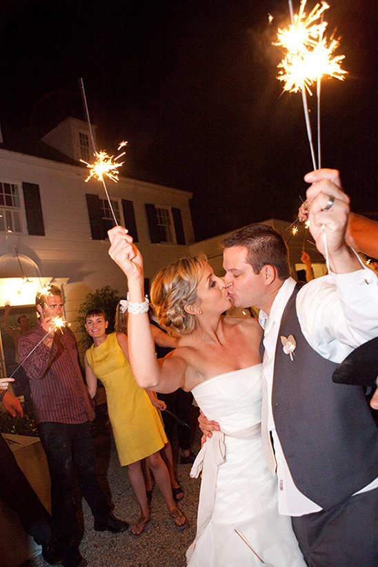 Newlyweds kiss under sparklers at a wedding celebration