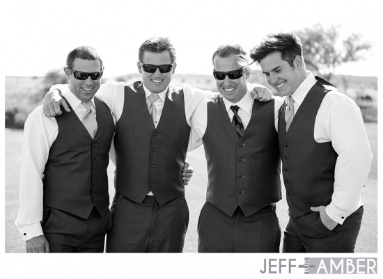 Groomsmen in vests and sunglasses celebrate in black and white