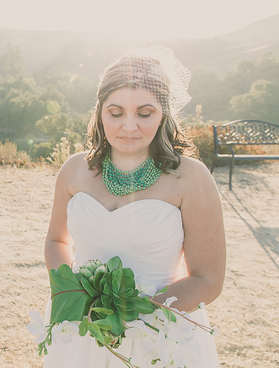 Bride in white dress with green necklace and bouquet