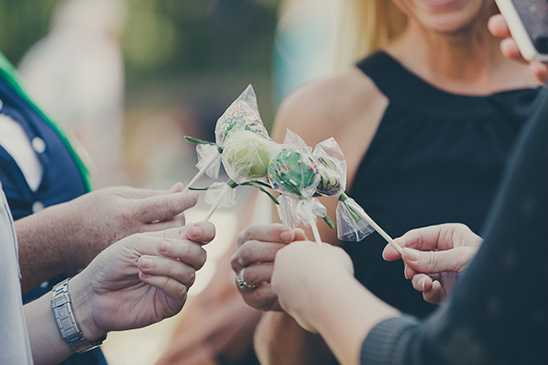 People holding cake pops on sticks at an outdoor event