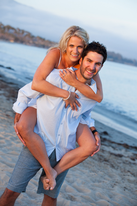 Happy couple at beach, man giving woman piggyback ride
