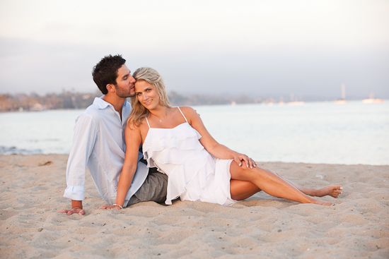 Couple on beach with man kissing woman on the head