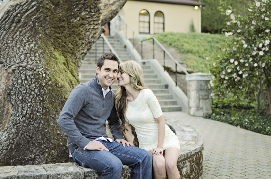 Happy couple cuddling near a stone wall and tree
