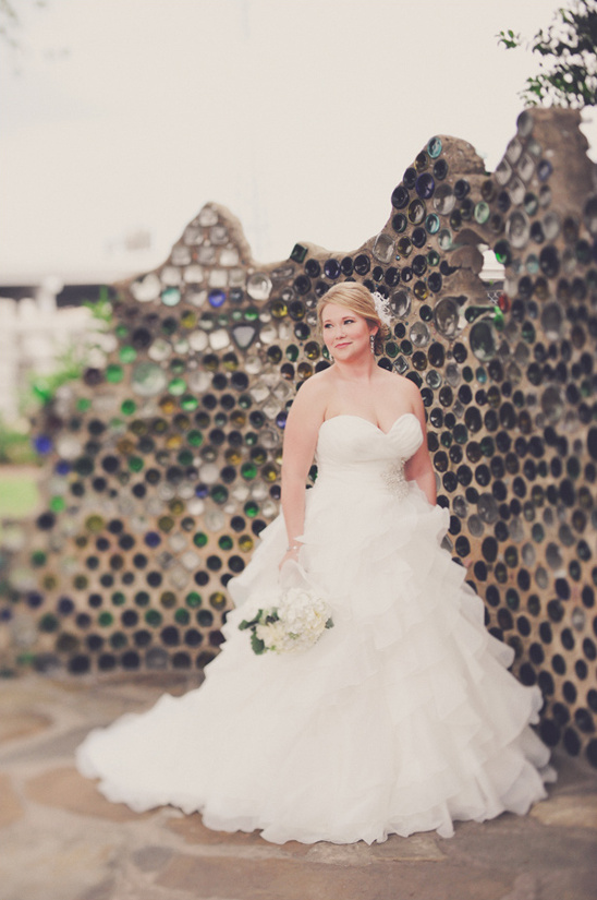 Bride in wedding dress by bottle wall