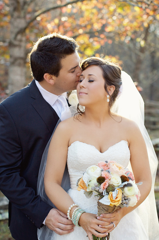 Groom kisses bride on forehead, autumn wedding