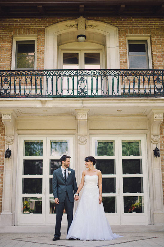 Happy wedding couple posing in front of mansion