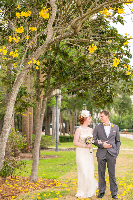 Happy bride and groom stroll under yellow blossoms