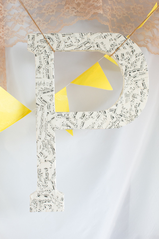 Large letter P decorated with music notes and yellow bunting