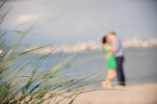 Blurry seaside couple embracing, beach grass in foreground