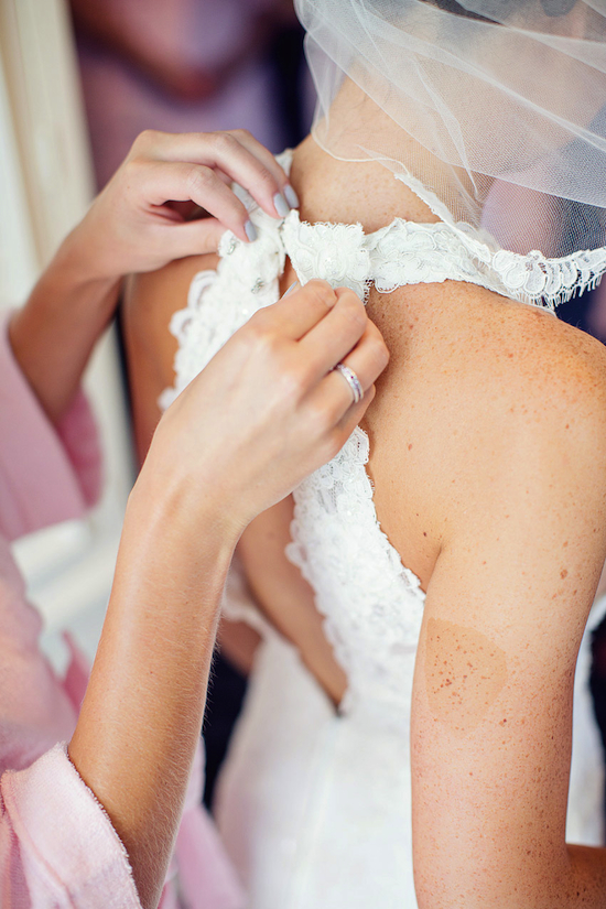 Bride getting dressed in lace wedding dress