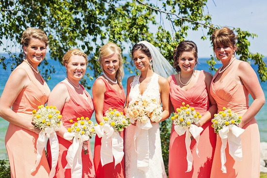 Bride and bridesmaids in coral dresses hold bouquets