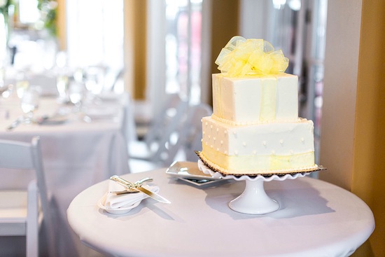 Yellow ribbon wedding cake on stand