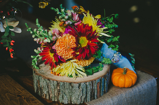 A colorful autumn bouquet with a small pumpkin on a wood slice