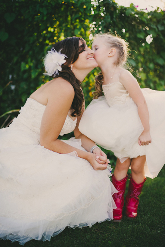 Bride and flower girl share a kiss in a garden, happy wedding day