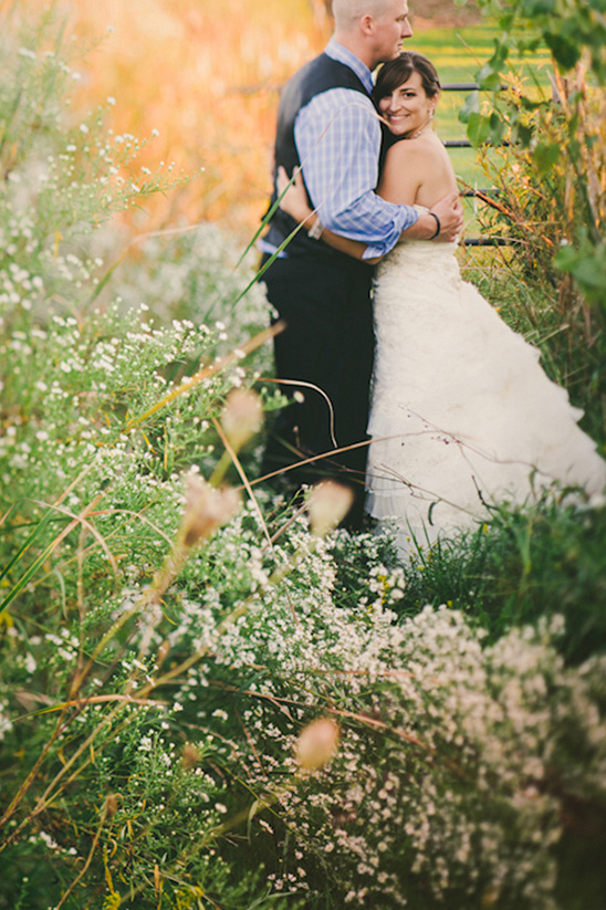 Bride and groom embrace amidst wildflowers on their wedding day