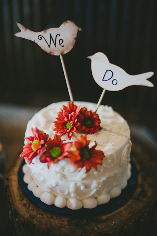 Wedding cake with We Do bird toppers and red flowers