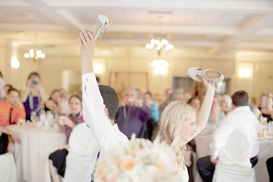 Couple raising shoes at wedding reception, celebrating love
