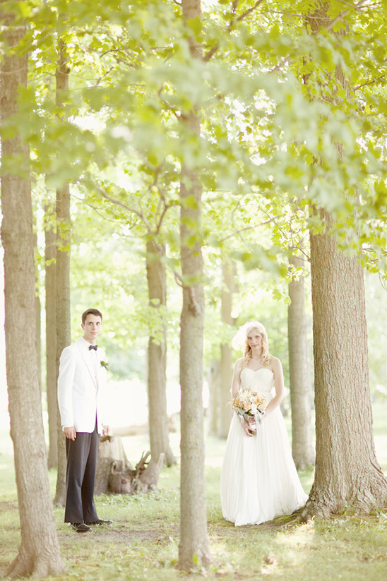 Bride and groom standing in a sunlit forest on their wedding day