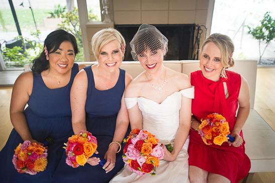 Bride with bridesmaids in bright dresses holding flower bouquets
