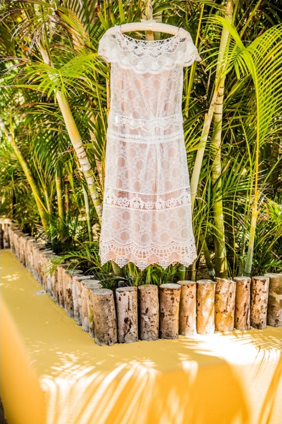 Delicate white lace dress hanging among lush tropical plants