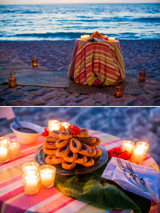 Romantic beach dinner setting with candles and churros