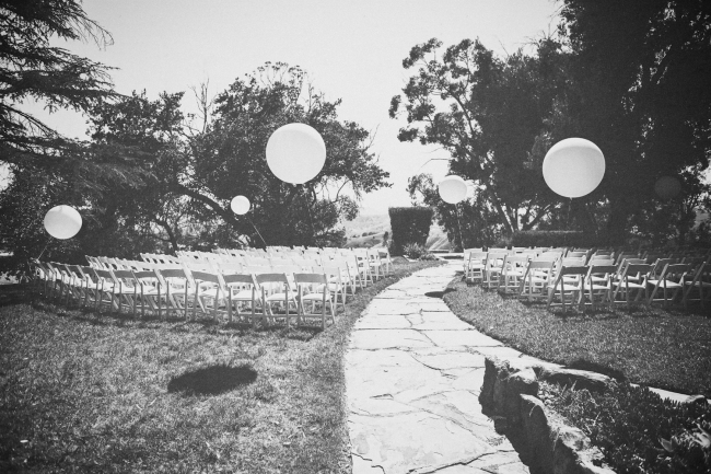 Wedding ceremony setup with balloons and pathway in a garden