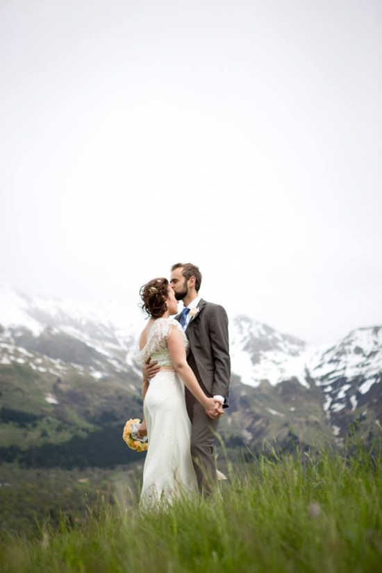 Couple kisses on a mountain wedding with scenic snowy peaks