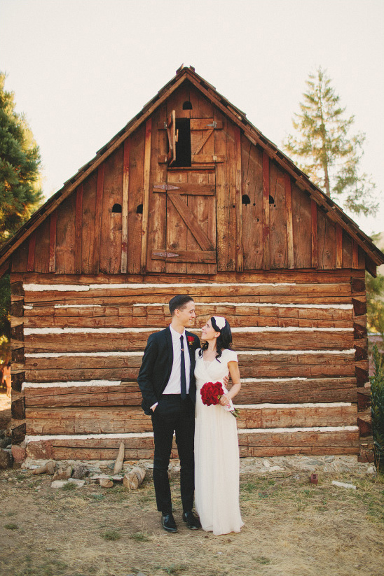 Wedding couple posing in front of rustic wooden barn