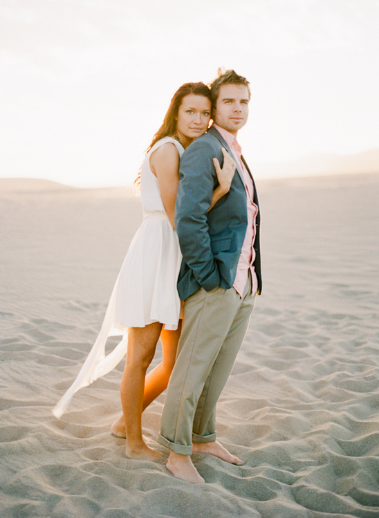 Couple embraces on sandy beach at sunset, soft focus