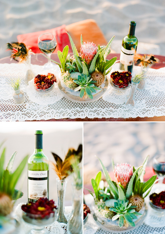 Beach picnic setup with wine and flower arrangement