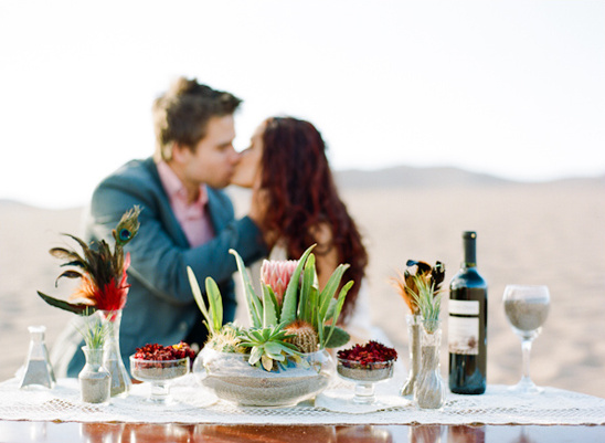 Romantic desert wedding with couple kissing at the table