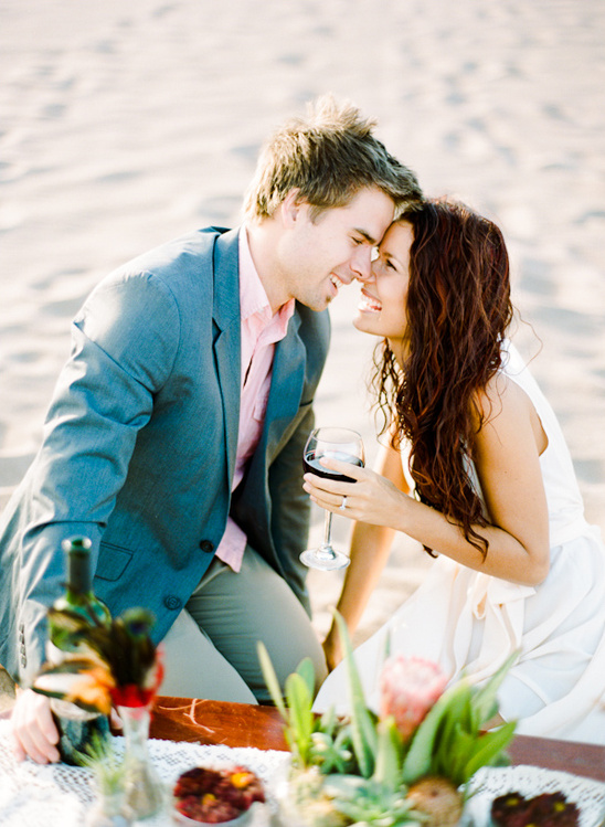 Romantic couple enjoying wine and picnic on the beach