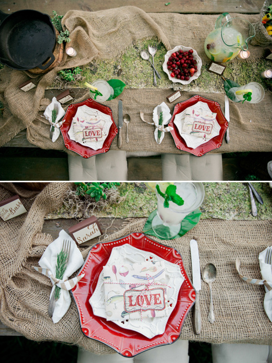 Rustic outdoor wedding table setting with red plates and love decor
