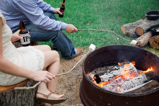 People toasting marshmallows around a cozy campfire with beer