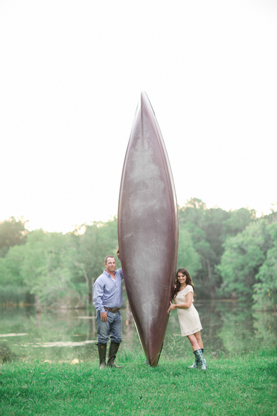 Couple standing next to a canoe by the lake shore, happy outdoors