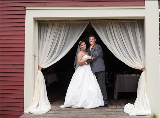 Happy couple smiling at wedding in a rustic barn doorway
