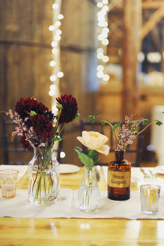 Elegant floral table setting with vintage bottles and fairy lights