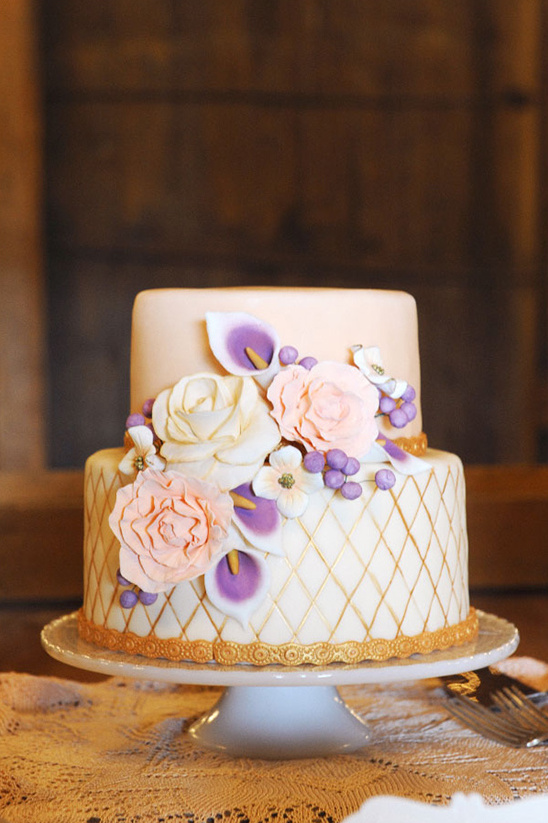 Elegant two-tiered wedding cake decorated with flowers and gold details