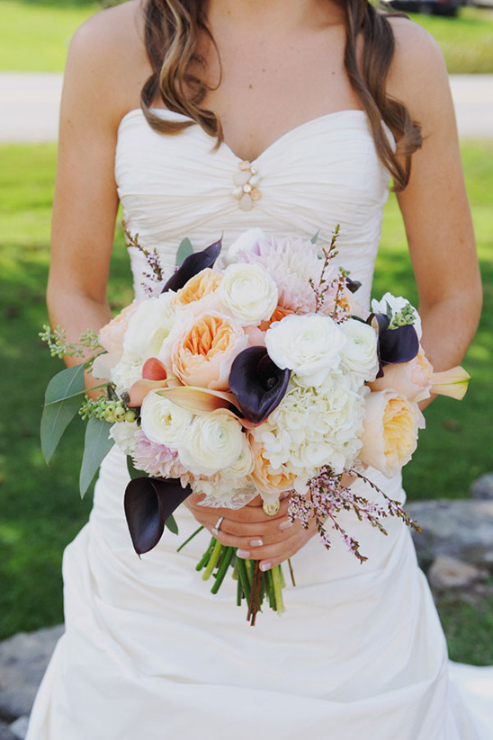 Bride holding colorful wedding bouquet and wearing a white gown