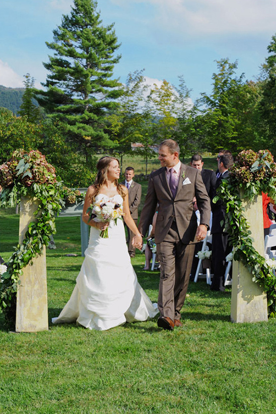 Happy couple walking down the aisle after their beautiful outdoor wedding